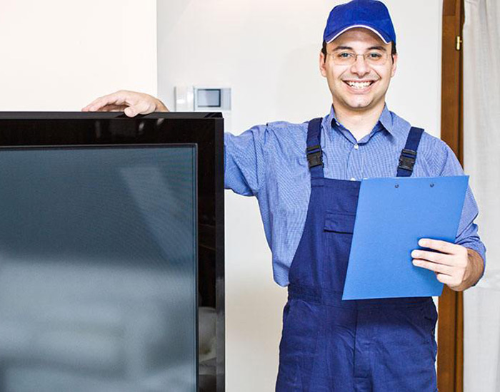 smiling repairman standing next to flat screen TV